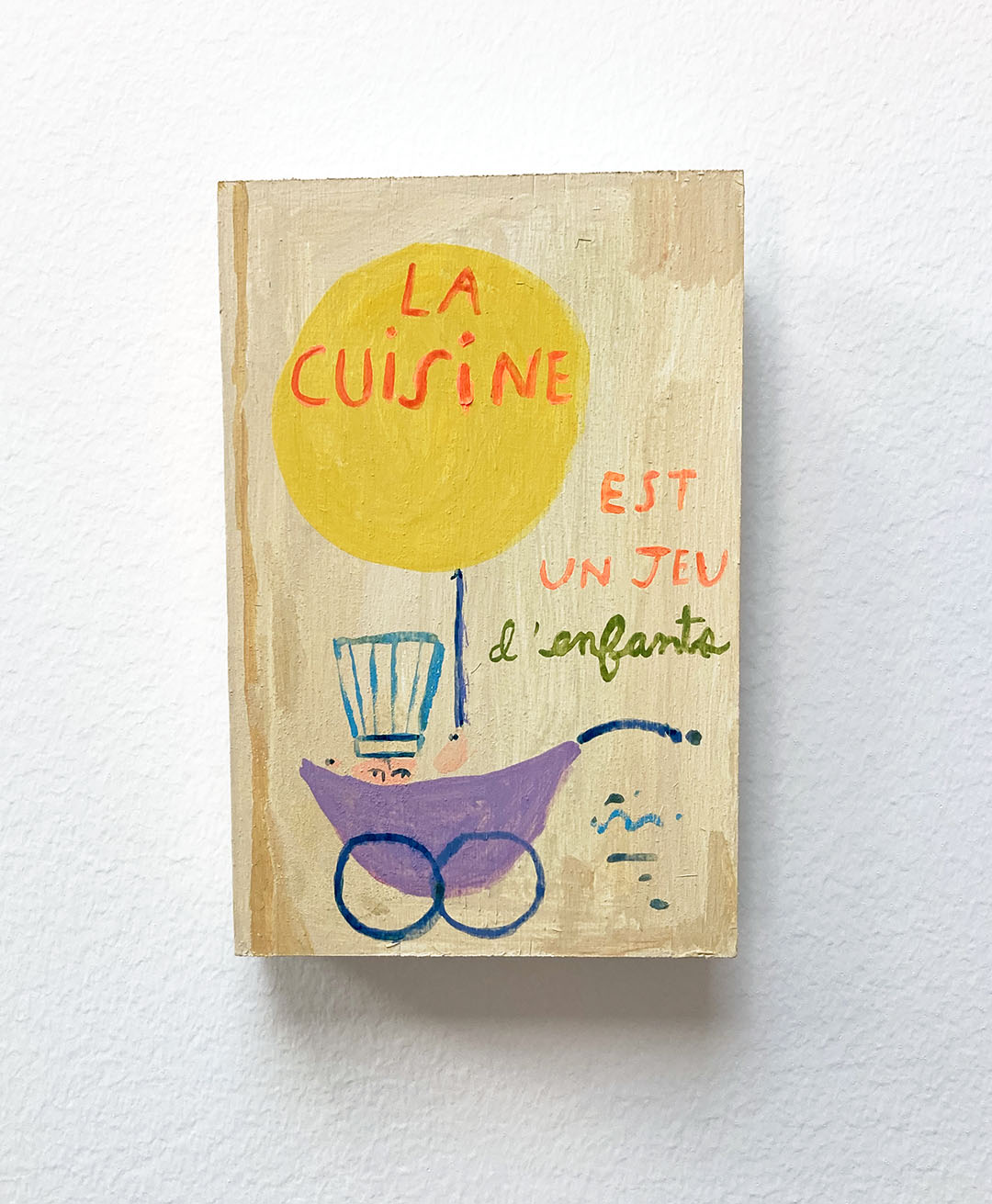 La Cuisine est un jeu d'enfants Cookbook, painting on wood block.