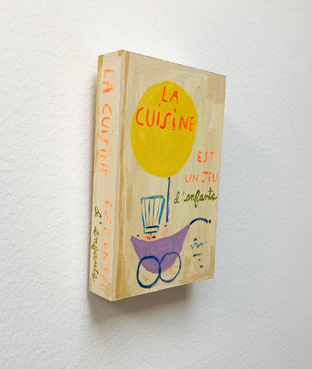 La Cuisine est un jeu d'enfants Cookbook, painting on wood block.